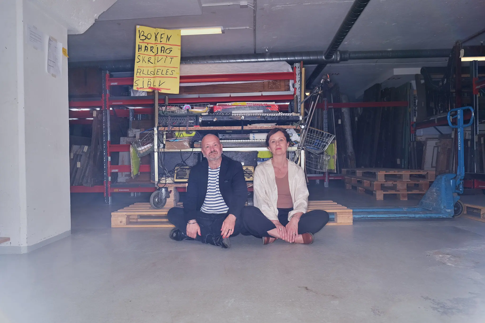 Man och kvinna sitter på golv i lagerlokal
